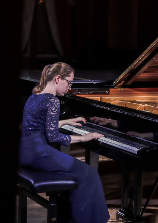 młoda kobieta w niebieskiej sukni grająca na fortepianie