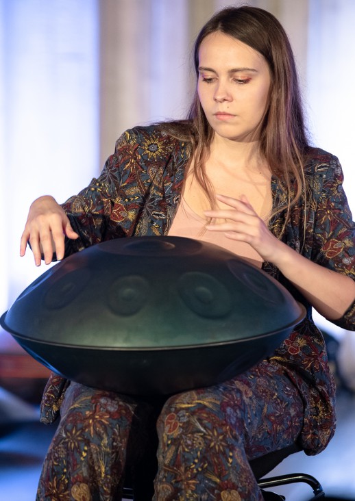 siedząca kobieta gra na instrumencie muzycznym handpan