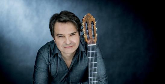 portret mężczyzny w szarej koszuli opartego o gryf gitary