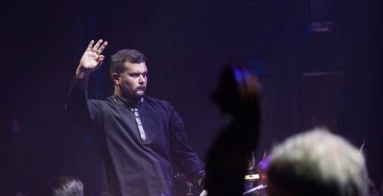 a young man conducting the orchestra with a raised hand