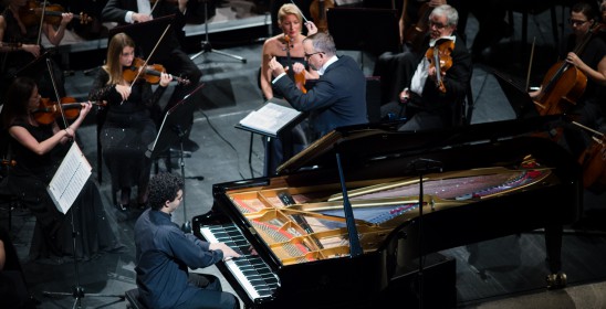a man playing the piano and a conductor with his hands raised