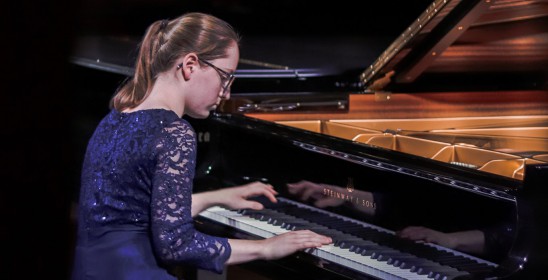 young woman in a blue dress playing the piano