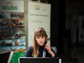 Festiwal Nova Muzyka i Architektura kobieta grająca na instrumencie muzycznym, pierwszy plan skierowany na pulpit, w tyle rollup sponsorów/partnerów  wydarzenia