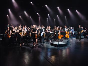 muzycy Toruńskiej Orkiestry Symfonicznej stojący na scenie Sali Koncertowej 