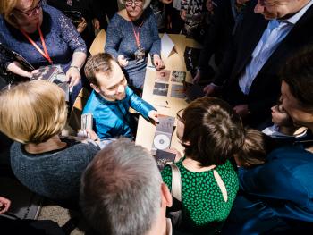 Viva Beethoven! - 250. rocznica urodzin kompozytora solista w turkusowej koszuli, siedzący przy stole rozdaje autografy, widok z góry, obcujący tłum wielbicieli