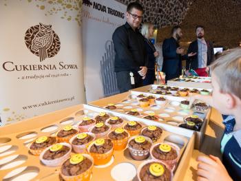 Koncert z okazji Dnia Dziecka małe babeczki na stole, poczęstunek na koncercie dla dzieci, w tle rollup Cukierni Sowa