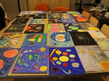 Prace plastyczne dzieci na stole, z przodu niebieskie prace z planetami