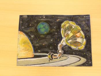 Praca plastyczna dziecka przedstawiająca planetę Saturn i jego pierścień, na którym znajduje się patefon