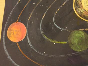 Praca plastyczna dziecka przedstawiająca planety na orbitach. W planetach przedstawione są porterty kompozytorów