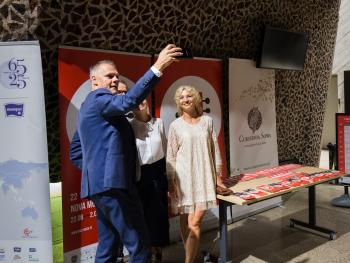 Festiwal Nova Muzyka i Architektura mężczyzna i dwie kobiety elegacko ubramni, robia sobie zdjęcie na tle rollupów ustawionych na foyer sali koncertowej