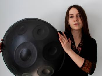 young woman in a black blouse with a handpan holding a instrument