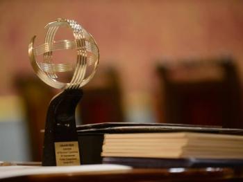 Statuetka dla laureata pierwszej nagrody konkursu wykonana ze srebra w kształcie astrolabium stojąca na stole.