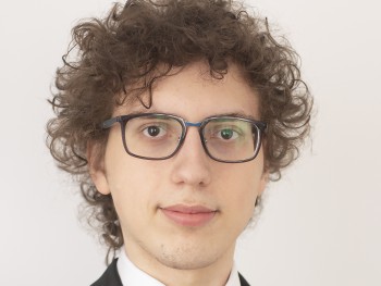 Miłosz Rządkiewicz portret młodego mężczyzny o kręconych włosach, w okularach