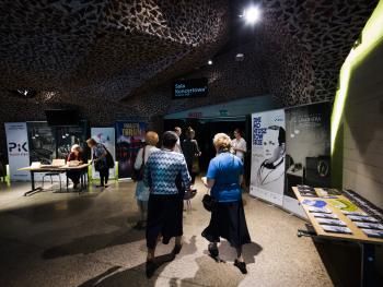 Dni Moniuszkowskie foyer sali koncertowej, melomani kierują się w kierunku wejścia głównego, po prawej stronie znajduje sie stół z ekspozycja materiałów promocyjnych dot Dni Moniuszkowskich, po lewej rollupy sponsorów