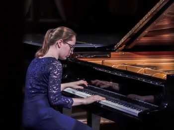 Karolina Sekuła kobieta w granatowej sukni grająca na fortepianie