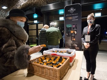 Kobieta w płaszczu pobierająca pierniki z kosza, w tle wyjście główne z CKK Jordanki Fabryka Cukiernicza Kopernik S.A.