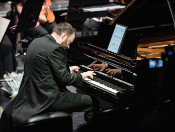 pianista grający na scenie podczas koncertu, na fortepianie widoczny jest tablet wyświetlający nuty