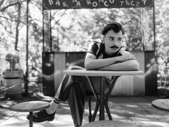 Wiktor Dyduła, fot. Zosia Zija i Jacek Pióro mężczyzna opierający sie o stolik