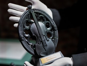 Statuetka Muza Tos-u 2025 dla Toyota Bednarscy Toruń czarna statuetka trzymana w dłoniach w białych rękawiczkach
